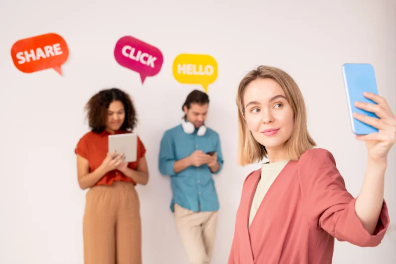 grupa młodych ludzi postuje w social mediach i zastanawia się czy warto prowadzić profil firmowy